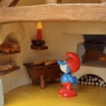 Papa smurf looking at croissants inside a miniature bread oven
