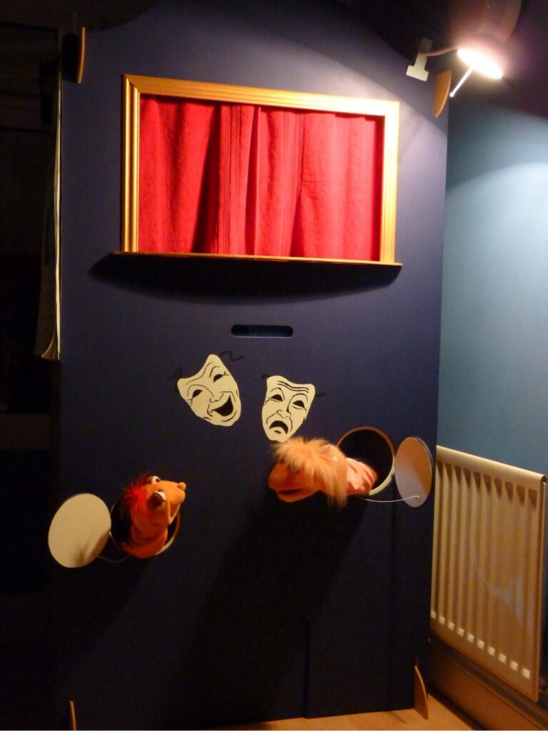 home-made puppet theatre with red curtain and comdy and tragedy masks