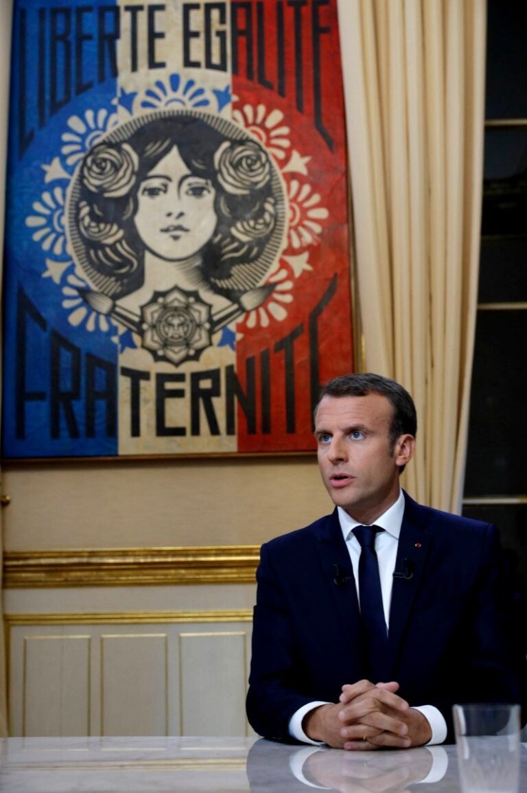 Emmanuel Macron in front of painting "Liberté, Egalité, Fraternité" by Shepard Fairey